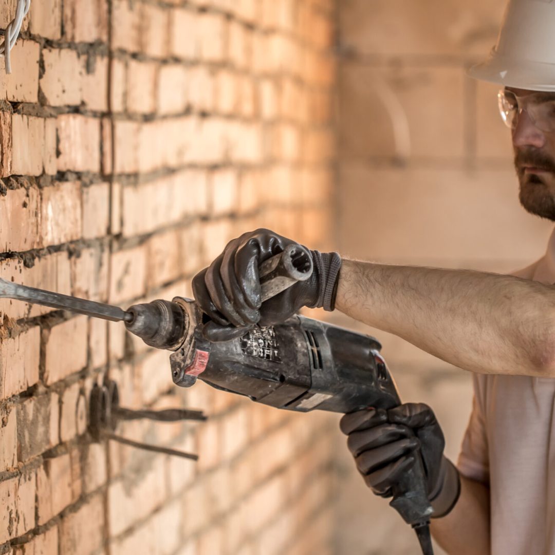 Handyman uses jackhammer, for installation, professional worker on the construction site. The concept of electrician and handyman. House and house reconstruction. SSUCv3H4sIAAAAAAAACpyRwW7DIAyG75P2DhHnRgqQdG1fpdrBAdqgUqiAbJqqvvsMhInzbviz/du/eb6/dR2ZIWhBTt0zRRhrY9YQPUTtLOJht3GvrFS+JUrq6LwG08IZolgs3BVCuxqT8CsnSYgQ16BCGrYhAVFdUaPAP4my0bnEXU3kJHZgipBdw8I6Z1ZREf9XZ3l8VjdwVVb85IUbI14ZBcXIuZSS23dU/t5ag1Vq17j6cgJMKuCN0sNroe21aXNxyVeubcKtNvq0AmH0WJcnxrkHzCZd+YKyqvIFQsAOWXkzS+C3unszyrqYPWwnIRI/I4WUMzqy6YOycTqw434YtoLygYtGnbxRFcJY3LRs3eu0AVHzJLnirB8nwfuRX/b9ASTtGaXDNNHjgdMRb//6BQAA//8DADUhqzOKAgAA